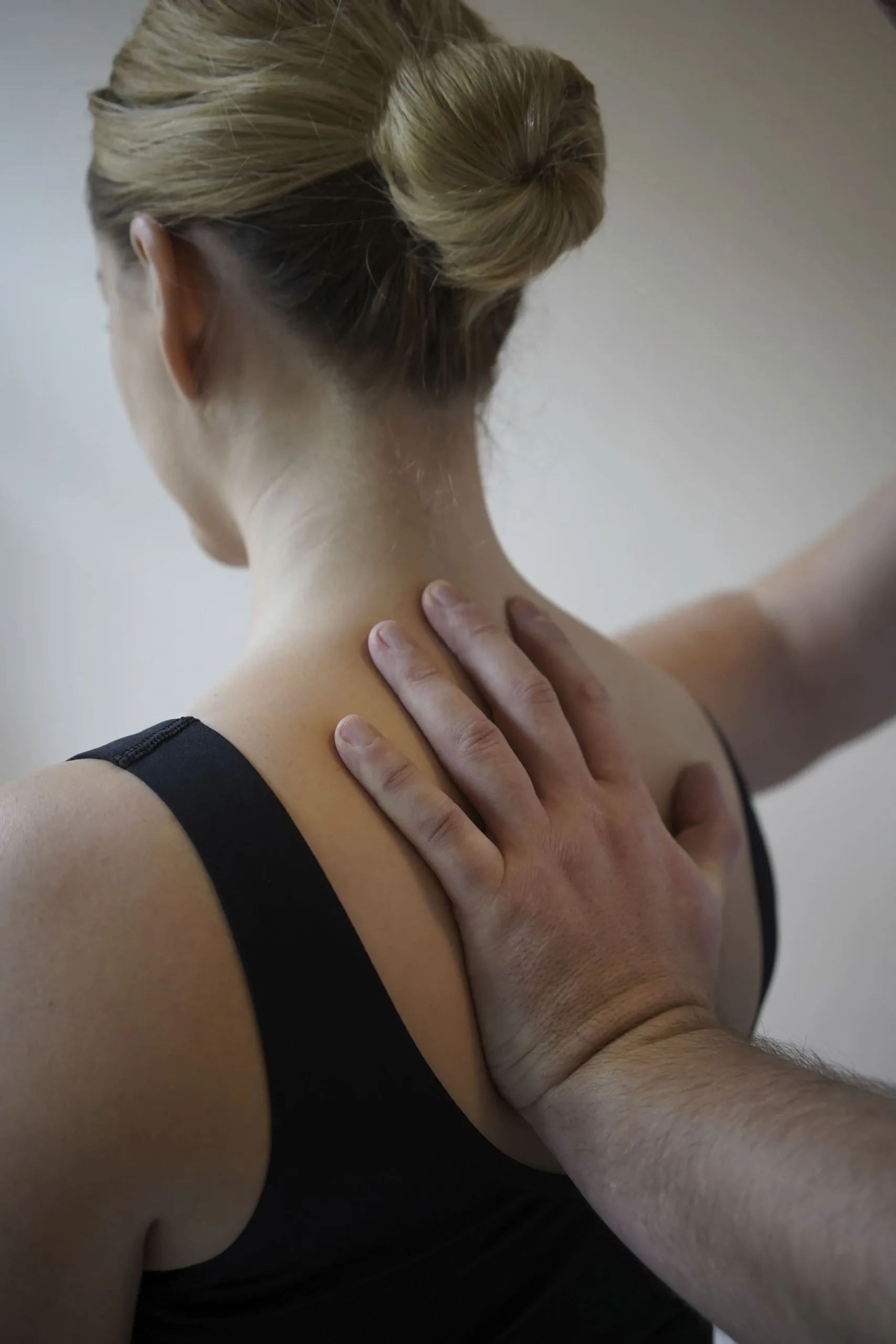 Eine Hand liegt auf dem Rücken einer Frau, die ein schwarzes Trägerhemd trägt.